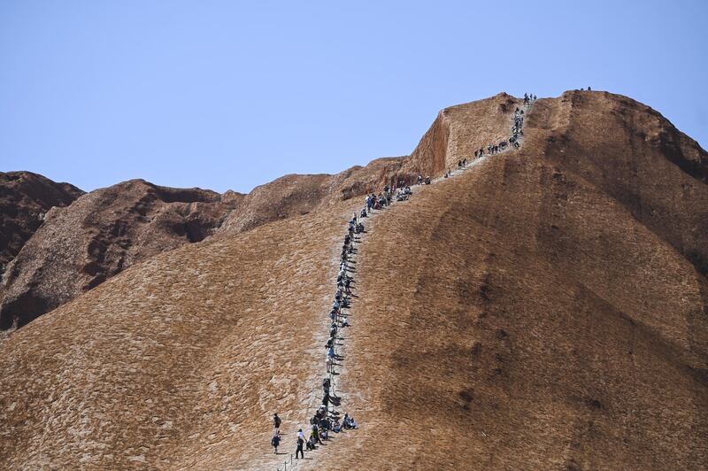 Tourists climb Uluru. EPA