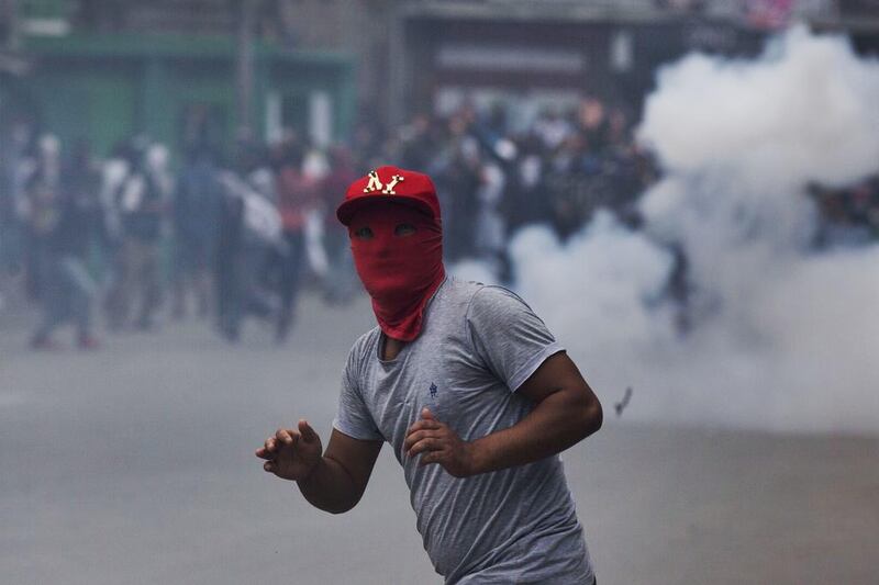 A masked Kashmiri Muslim protester watches for teargas shells fired at him by Indian police men during a protest in Srinagar.  Dar Yasin / AP Photo