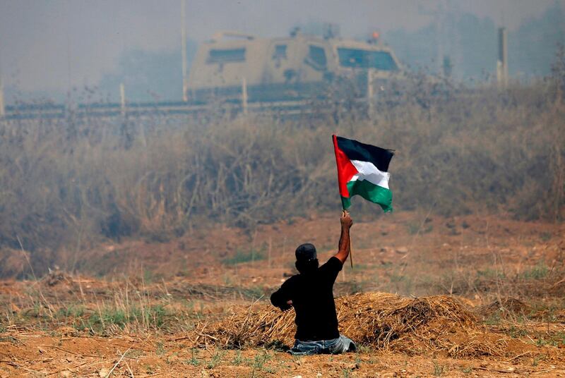 (FILES) This file photo taken on May 19, 2017 shows handicapped Palestinian demonstrator Ibrahim Abu Thurayeh waving a Palestinian flag during clashes with Israeli soldiers following a protest against the blockade on Gaza, near the border fence east of Gaza City.
The 29-year-old Abu Thurayeh was shot during clashes with Israeli security forces against Washington's recognition of Jerusalem as Israel's capital, on December 15, 2017 the Palestinian health ministry said, shortly after another man was killed in similar circumstances. / AFP PHOTO / MOHAMMED ABED
