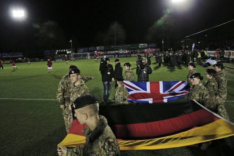 British Army cadets carry out the national flags of England and Germany onto the pitch prior to Wednesday's football match in Aldershot commemorating 100 years since the Christmas Day Truce of World War I. Lefteris Pitarakis / AP