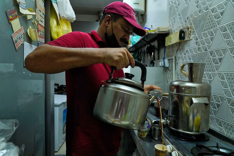An Indian tea seller who gave his name as Rafik pours karak in Dubai, United Arab Emirates, Wednesday, Aug.  24, 2022.  Karak is the informal national drink of the United Arab Emirates, long priced at just 1 dirham, a bit less than 30 U. S.  cents.  But now, as supply chain shortages and Russia's war on Ukraine lead to price spikes across the world, Dubai's tea sellers are bumping up prices to 1. 50 dirhams, or just over 40 cents.  That's a blow to migrant workers who depend on the drink as a daily ritual offering respite and fuel.  (AP Photo / Jon Gambrell)