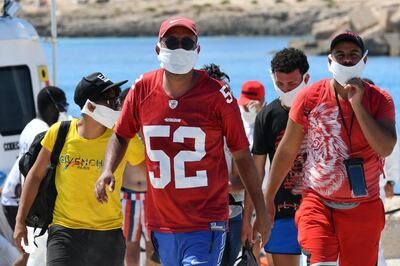 Migrants from Tunisia disembark from Italy's Guardia Costiera (Coast Guard) boat in the Italian Pelagie Island of Lampedusa on July 30, 2020.

 Nearly half of the 11,000 or so migrants who had made shore in Italy as of last week had set off from Tunisia, and most of those were Tunisian citizens, official figures show. Italy's Interior ministry said it was finding the migrant situation "much more complex" than in previous years, and was upping returns to Tunisia as it struggled to house new arrivals. / AFP / Alberto PIZZOLI
