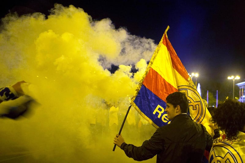 Real Madrid fans celebrate after lighting a flare in downtown Madrid, Spain. Paul White / AP Photo