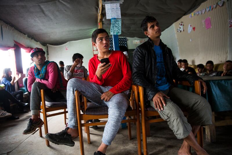 Migrant children watch a movie inside the Jungle Books Cafe in the camp