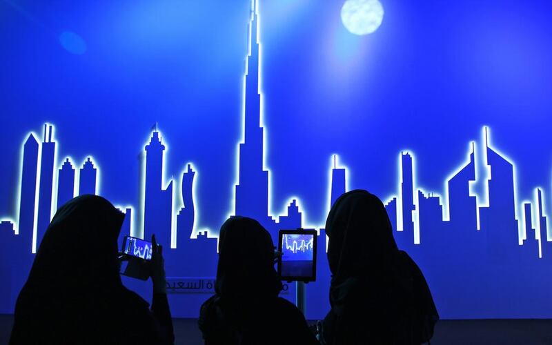 Emirati attendees take photos of an image of the city’s skyline in Dubai. After years of chasing the biggest and the best, Dubai is turning to technology to help the little things in life run more smoothly. Kamran Jebreili / AP Photo