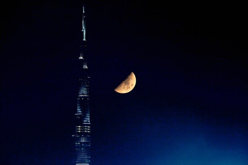 Dubai - August 16, 2010 - The moon in its first quarter phase begins to set as it appears close to the Burj Khalifa in Dubai, August 16, 2010. Neap tide, when the tide-generating forces of the sun and moon oppose each other they produce the smallest difference between high and low tide, which occurs during the first and third quarter phase of the moon. (Photo by Jeff Topping/The National) STOCK