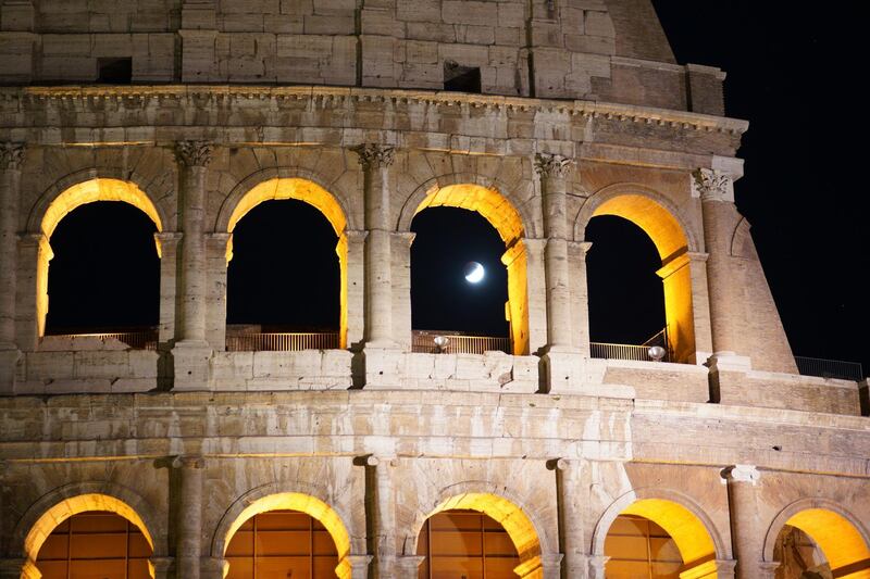 People watch a rising moon in Rome. AP Photo/Andrew Medichini