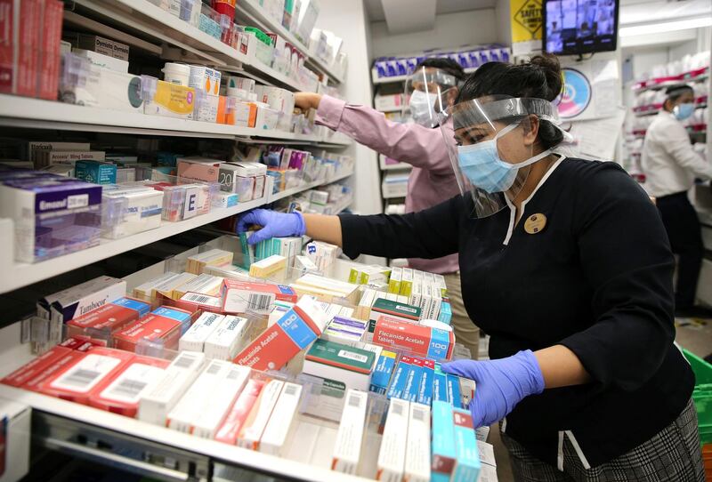 A pharmacy assistant inside a UK Boots store prepares medicines for a cyclist to deliver to vulnerable people in east London. AFP