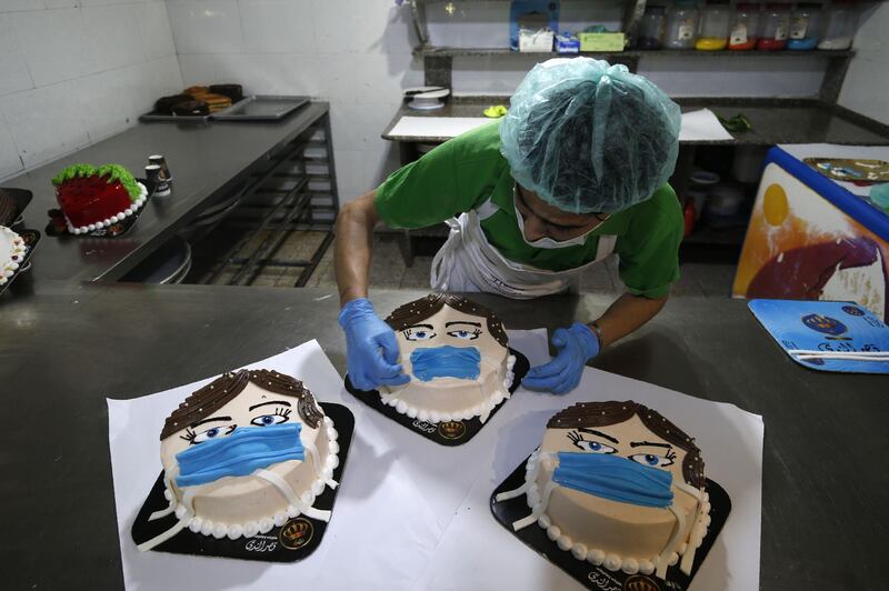 A Palestinian baker finishes a cake, that portrays a woman wearing a facemask, at his shop in Khan Yunis in the southern Gaza Strip.   AFP