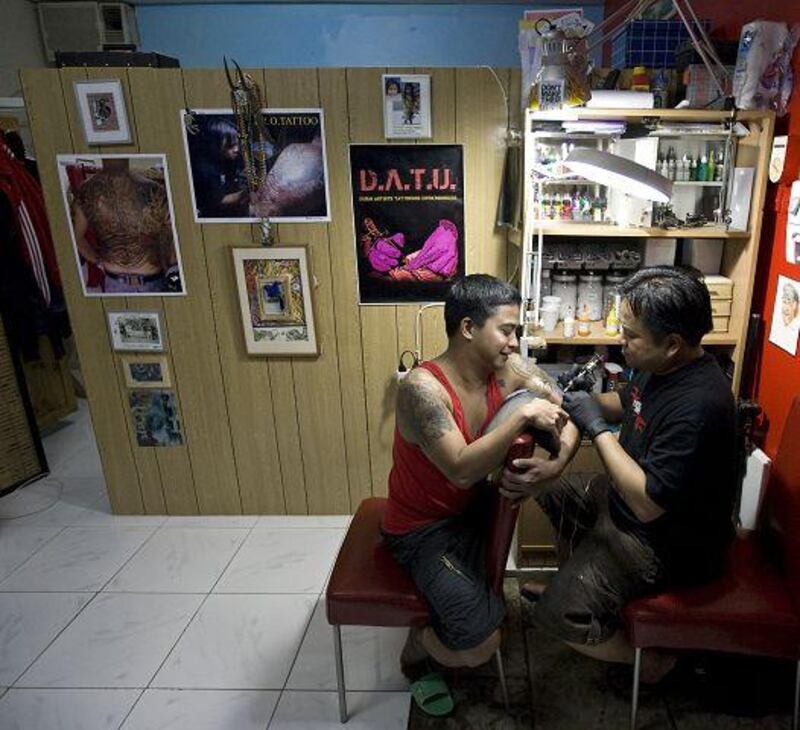 Glen Hipolito, a tattoo artist in Dubai, inks Aries Manzo's arm.