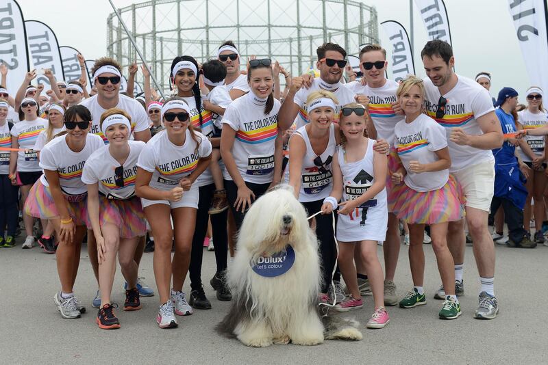 MANCHESTER, ENGLAND - JULY 21:  The cast of Hollyoaks pose with Dulux the Dog prior to The Color Run presented by Dulux, known as the happiest 5km on the planet on July 21, 2013 in Manchester, England. Runners of all shapes, sizes and speeds start wearing white clothing that is a blank canvas for the kaleidoscope of colours they encounter around The Color Run course. At each kilometre a different colour of powder is thrown in the air with the runners becoming a constantly evolving artwork. At the end of the course runners are greeted by the Colour Festival where the air is filled with music and stunning coloured powder bursts creating a vibrant party atmosphere. www.thecolorrun.co.uk Media contact: alex.coulson@img.com  (Photo by Chris Brunskill/Getty Images for Dulux)