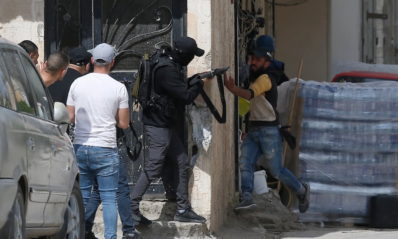 A man, right, takes shelter as a Palestinian man fires towards Israeli troops during the clashes. EPA