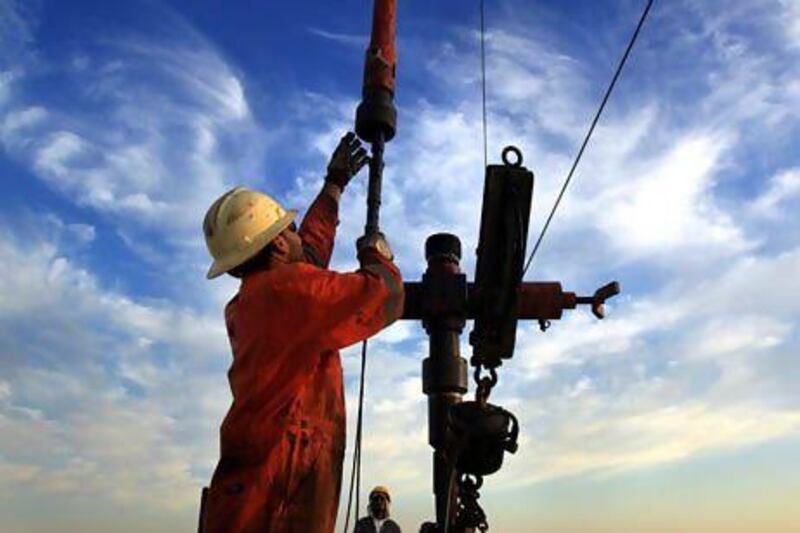 Brent crude dipped below $100 per barrel to its lowest price since July overnight on Monday. Above, workers make adjustments on an oilfield in Bahrain. Hasan Jamali / AP Photo