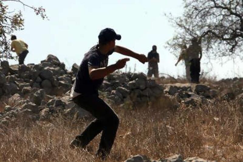 epa02261681 A Palestinian boy hurls stones to stop Israeli Settlers who attack the  village of Burin  near the West Bank City of Nablus   26  July ,2010 .The Israeli settlers were protesting the razing of illegally-installed mobile homes in the nearby Yitzhar settlement, setting fire to Palestinian olive trees in an apparent "price tag" reprisal for the demolitions.  Two Israeli Settler and three Palestinian wounded during clashes in the area .  EPA/ALAA BADARNEH