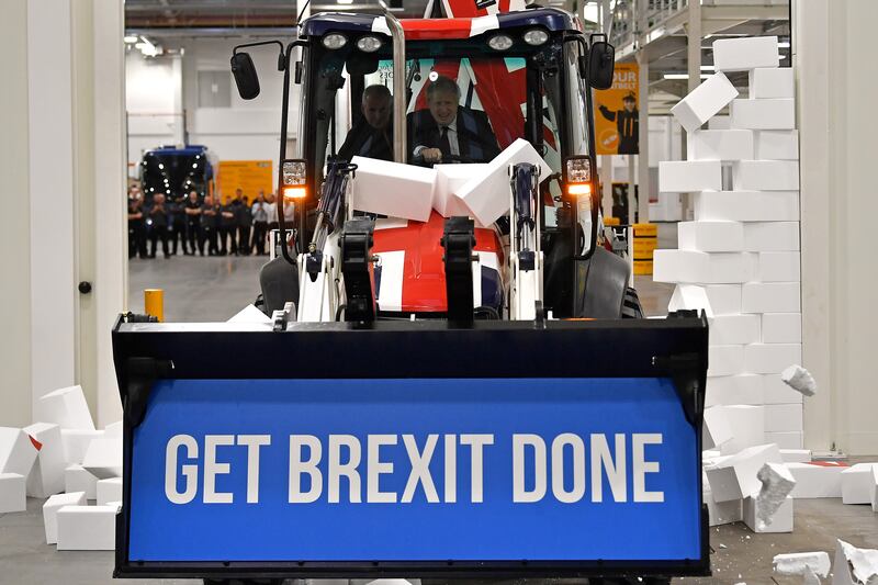 Mr Johnson drives a digger with the words 'Get Brexit Done' inside the digger bucket through a fake wall emblazoned with the word 'GRIDLOCK', during a general election campaign event in December 2019. Getty Images