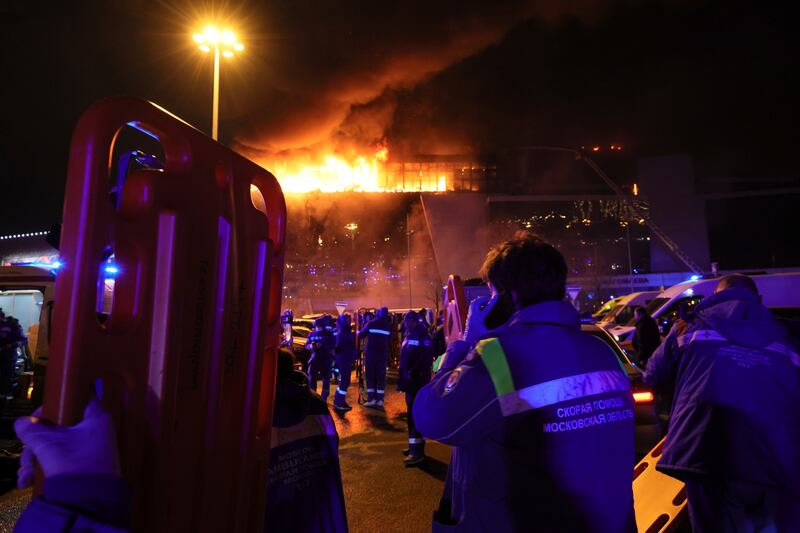 A medic stands near ambulances parked outside the burning concert venue. AP