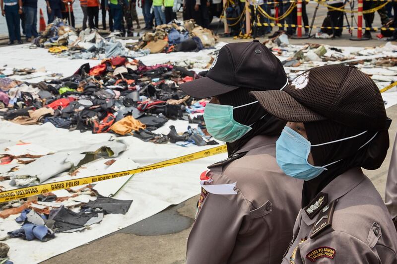 Indonesian police officers guard wreckage.