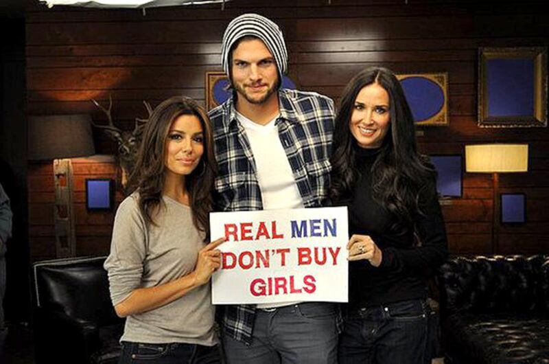 From left, Eva Longoria, Ashton Kutcher, Demi Moore hold up a sign reading Real Men Don’t Buy Girls in support of the kidnapped Nigerian girl students. May 2014. Courtesy Ashton Kutcher