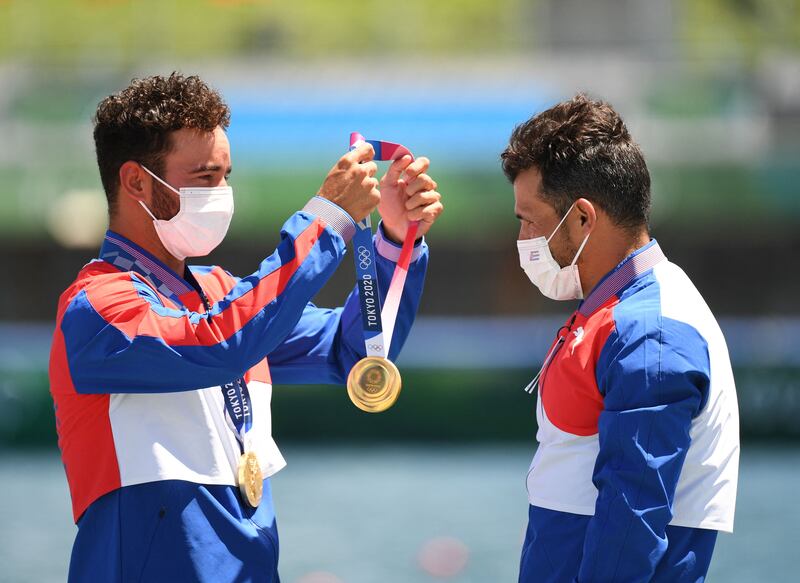Gold medallist Cuba's Serguey Torres Madrigal receives the medal from his teammate Cuba's Fernando Dayan Jorge Enriquez as they celebrates on the podium after the men's canoe double 1000m final.