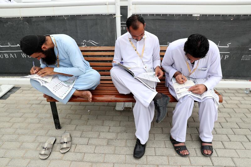 DUBAI , UNITED ARAB EMIRATES , MARCH 30  – 2018 :-  People looking at the race cards before the start of Dubai World Cup held at Meydan Racecourse in Dubai. ( Pawan Singh / The National ) For News/Sports/Instagram/Big Picture. Story by Amith/Rupert