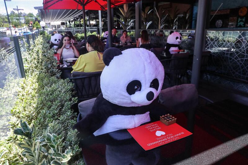 Plush toy pandas are placed at tables with a card reading "Leave this place empty for your health" in a restaurant in the Sogutozu district in Ankara.  AFP