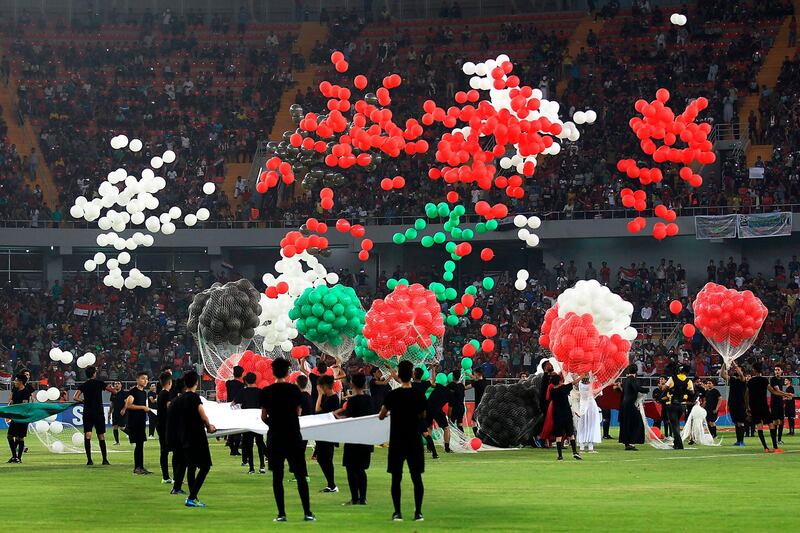 Performers release balloons during a ceremony ahead of a football match between Iraq and Lebanon in the West Asian Championship at the Karbala Sports City stadium in the central holy city of Karbala on July 30, 2019. A Lebanese violinist sparked controversy by playing the Iraqi national anthem on July 30 with her head and arms uncovered on the lawn of the Karbala stadium, a holy Shiite city in southern Iraq. / AFP / AHMAD AL-RUBAYE
