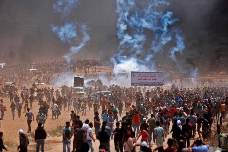Palestinians run for cover from tear gas. Mohammed Abed / AFP Photo