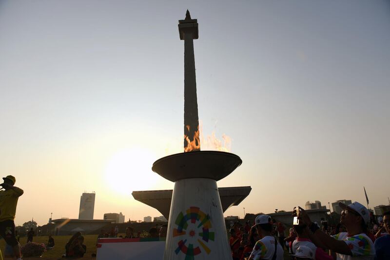 A runner (R) takes a picture of the 2018 Asian Games flame during the final day of the torch relay in Jakarta ahead of the opening ceremony for the 2018 Asian Games. AFP