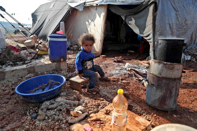 A child sits outside a tent at the flooded Mukhayyam Al Khair camp near the village of Kafr Uruq in the north of Idlib province on December 17, 2020. AFP