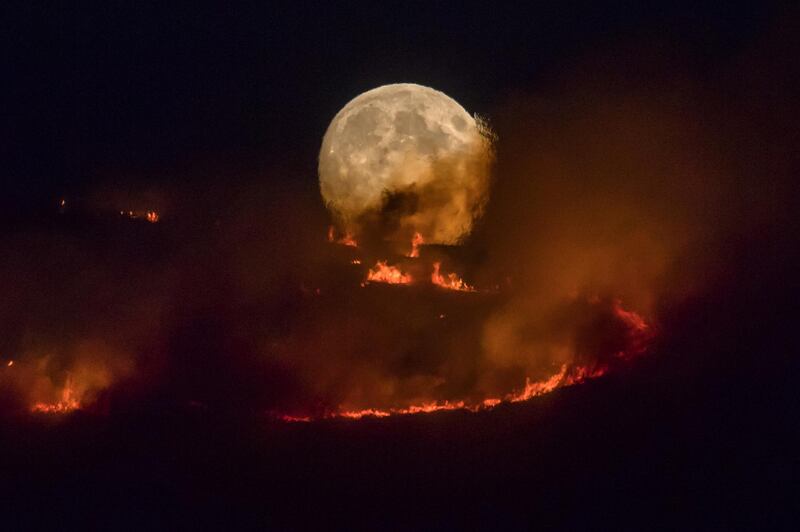 The full moon rises behind burning moorland as a large wildfire sweeps across the moors between Dovestones and Buckton Vale in Stalybridge, Greater Manchester in Stalybridge, England, on June 26, 2018. Anthony Devlin / Getty Images