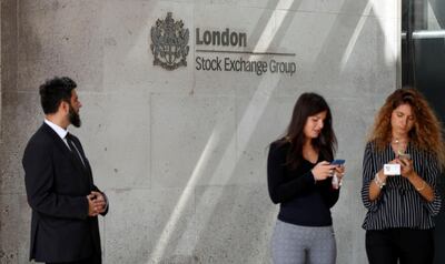 FILE PHOTO: People check their mobile phones as they stand outside the entrance of the London Stock Exchange in London, Britain. Aug 23, 2018. REUTERS/Peter Nicholls/File Photo
