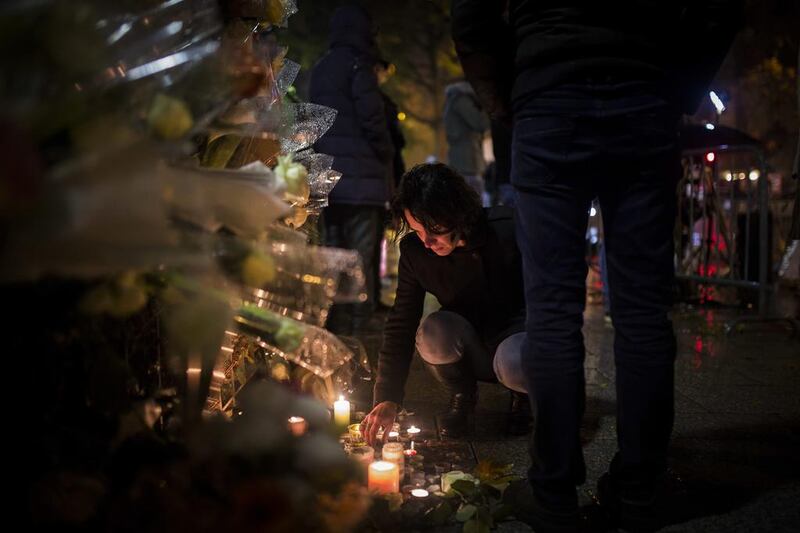 A woman lights a candle outside the Bataclan concert hall. Kamil Zihnioglu / AP Photo