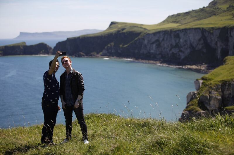 Tourists pose for photographs on the North Antrim Coast close to Carrick-a-Rede Rope Bridge where lies Larrybane headland. Larrybane was the dramatic spot chosen for Renly Baratheon's camp in Season 2 of Game of Thrones. Peter Morrison / AP Photo