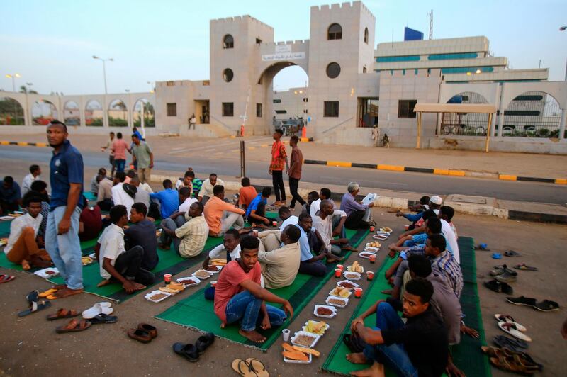 Sudanese men gather just before the time for breaking the fast during the holy month of Ramadan, in front of the military headquarters in central Khartoum. AFP