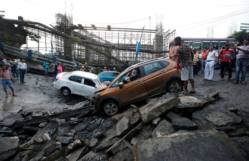 Onlookers stand next to the wreckage of vehicles at the site. Reuters