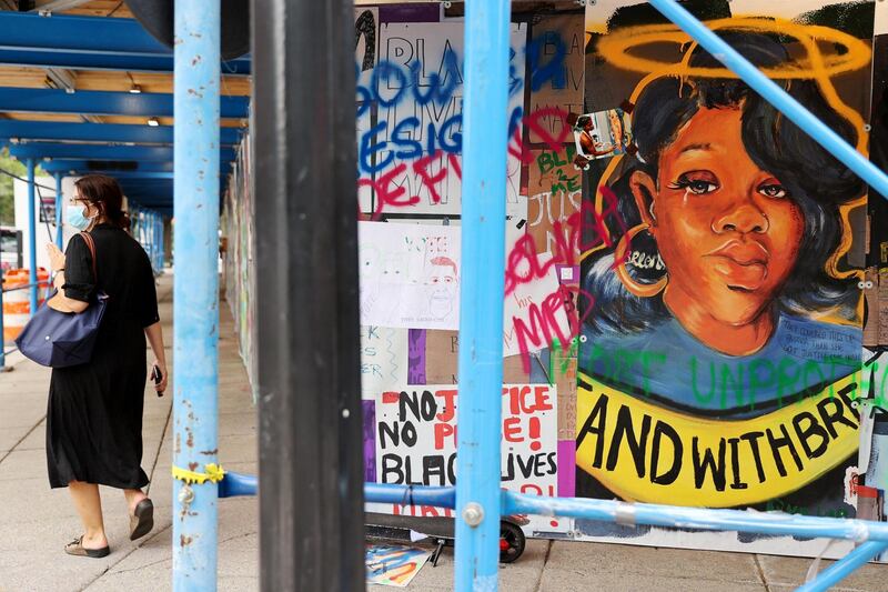 A woman walks near a wall of protest signs, including a portrait of Breonna Taylor - killed when drug investigators burst into her home in Louisville, Kentucky in March - at Black Lives Matter Plaza in Washington, U.S. REUTERS