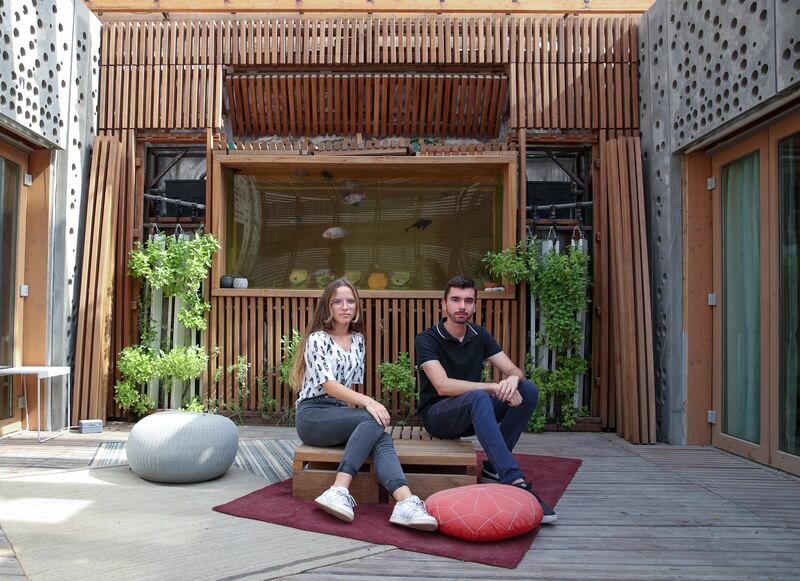 Noemie Jaupart and Axel Bule in front of the aquarium aquaponics wall.  