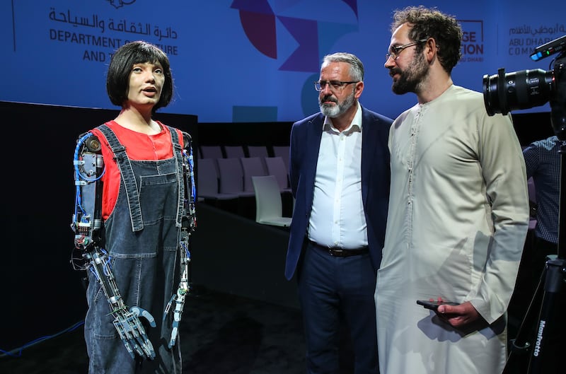 Robot artist Ai-Da, left, in conversation with The National's Hareth Al Bustani, far right, with her creator Aidan Meller, looking on. 
