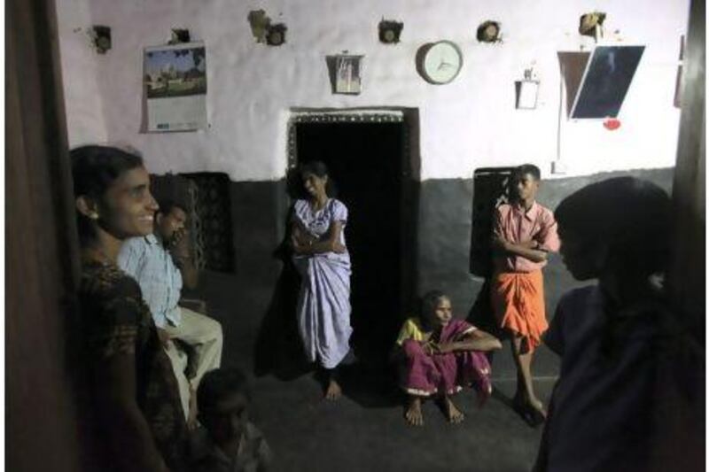Pushpa Gowda, centre, and her mother, Boommi Gowda, seated, shares a light moment with her family and neighbours the evening after they installed solar light in her house in Nada, on the outskirts of Mangalore. Rafiq Maqbool / AP Photo