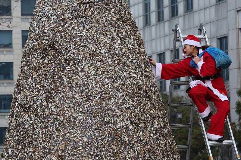 A member of Korean Federation for Environmental Movement in a Santa Claus outfit attaches dumped cigarette butts at a cigarette butt Christmas tree in front of Korea Tobacco & Ginseng Corporation office in Seoul, South Korea. The environmental activist group called for a ban on the use of plastic for cigarette filters as part of efforts to protect the environment from toxic plastic pollution. AP Photo