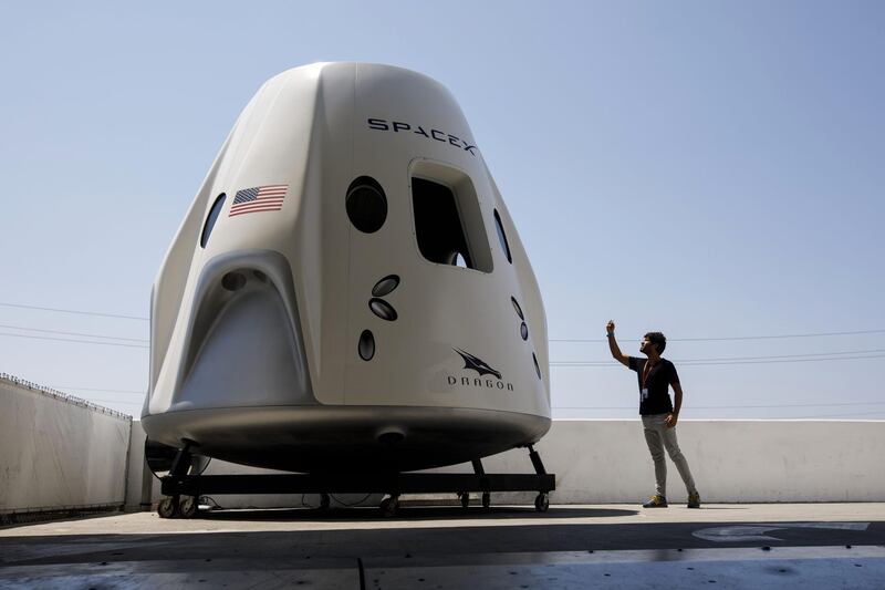 An attendee takes pictures of a mock up of the Crew Dragon spacecraft. Bloomberg