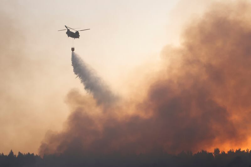 A chinook helicopter makes a water drop as a wildfire continues to rage in Varympompi, north of Athens.
