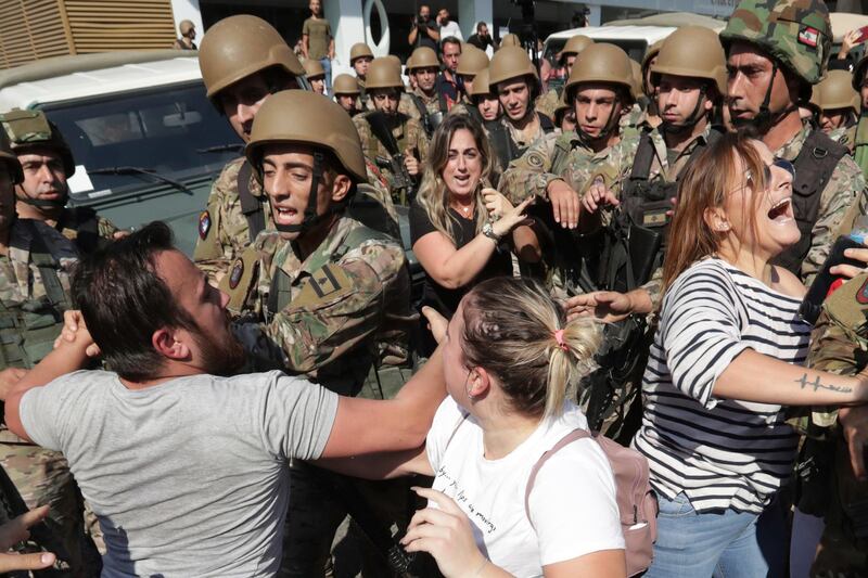 Anti-government protesters scuffle with Lebanese army soldiers during a protest in the town of Zouk Mosbeh, north of the capital Beirut, Lebanon, Tuesday, Nov. 5, 2019. Lebanese troops deployed in different parts of the country Tuesday reopening roads and main thoroughfares closed by anti-government protesters facing resistance in some areas that led to scuffles. (AP Photo/Hassan Ammar)