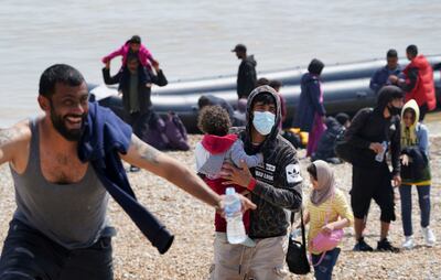 Migrants make their way up the beach after arriving on a small inflatable boat in Kent, England. AP 