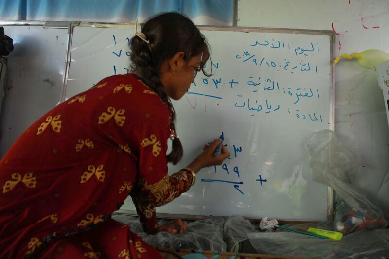 A displaced Syrian girl writes on a whiteboard.