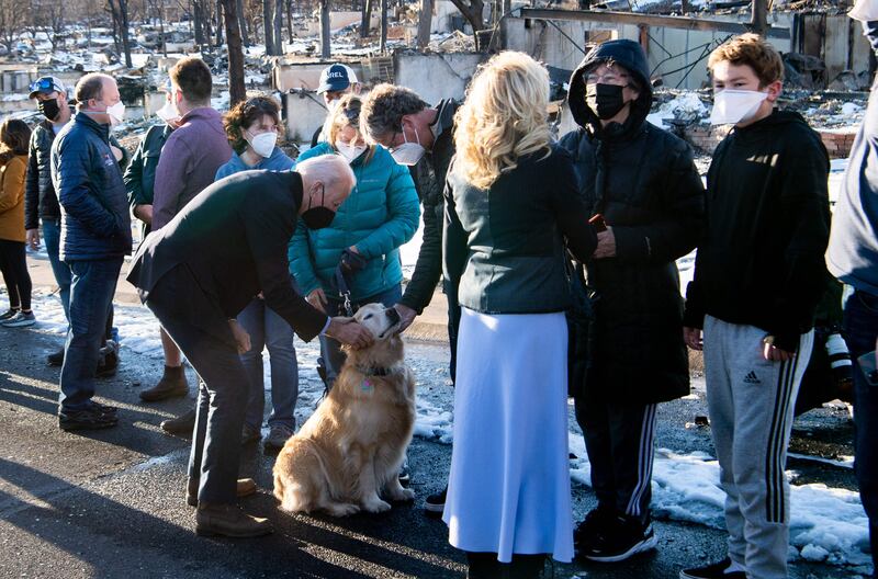 US President Joe Biden pets a dog as he and first lady Jill Biden meet with victims during a tour of a neighbourhood destroyed by the Marshall Fire in Louisville, Colorado, January 7, 2022.  AFP