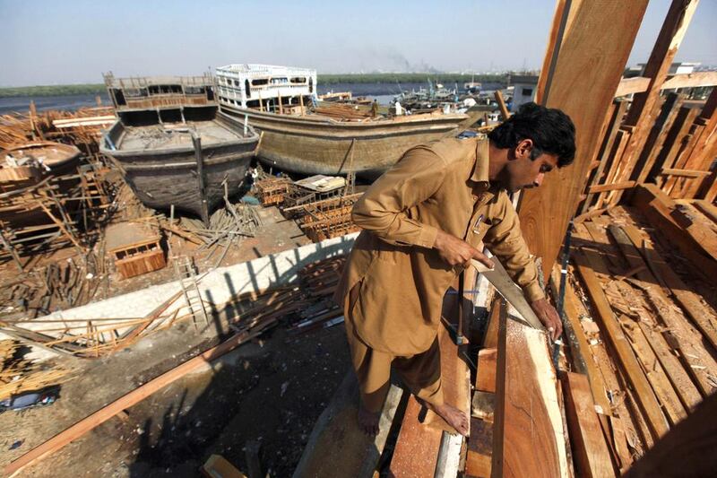 A carpenter cuts out a wood panel while working on a boat in Karachi's Fish Harbour. Akhtar Soomro / Reuters