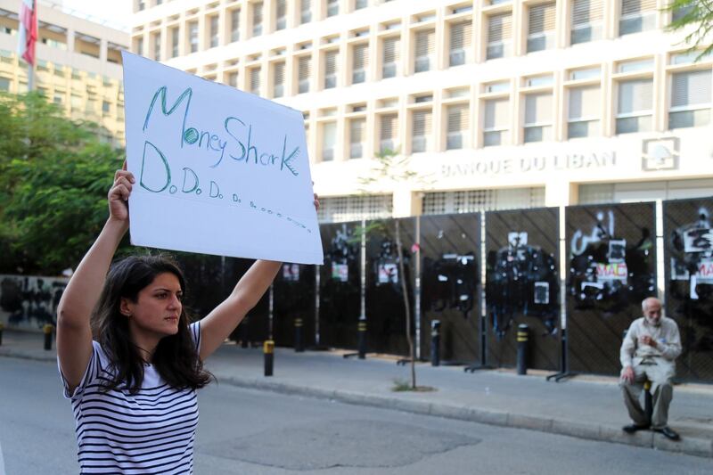 A protester holds a banner reading 'Money Shark' during a demonstration outside the Lebanese central bank, also known as Banque du Liban, in Beirut, Lebanon. Calls are mounting for Lebanon to impose formal restrictions on the movement of money to defend the country’s dollar peg and prevent a run on the banks when they open their doors on Friday after two weeks of nationwide protests. Bloomberg