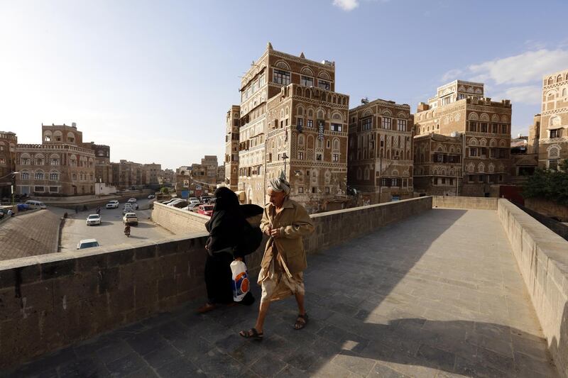 epa07626015 Yemenis walk past historical buildings on the last day of the Muslim fasting month of Ramadan, in Sana'a, Yemen, 04 June 2019. According to reports, the Houthi rebels, which currently controls the capital Sana'a and northern cities of war-torn Yemen, have declared that the Eid-al-Fitr festival would be on 05 June 2019, in opposition to the Saudi-backed Yemeni government that controls the southern cities of the Arab country.  EPA/YAHYA ARHAB