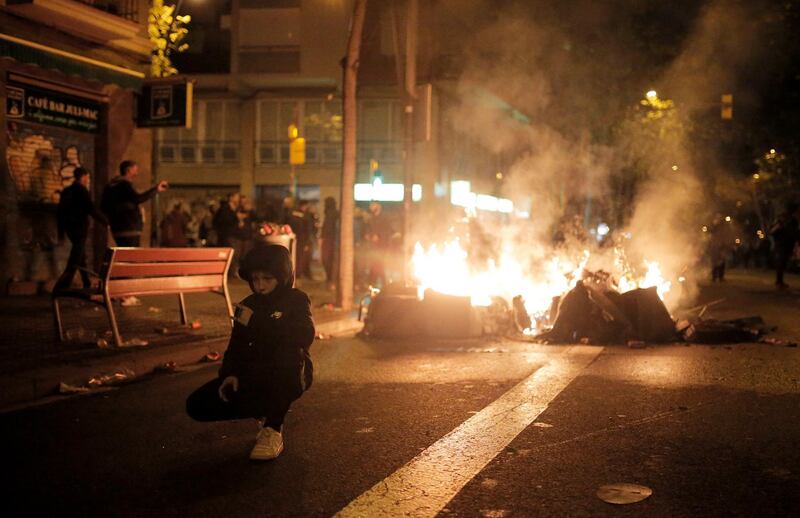 A boy poses in front of fires burning at the Catalan pro-independence protest. AP